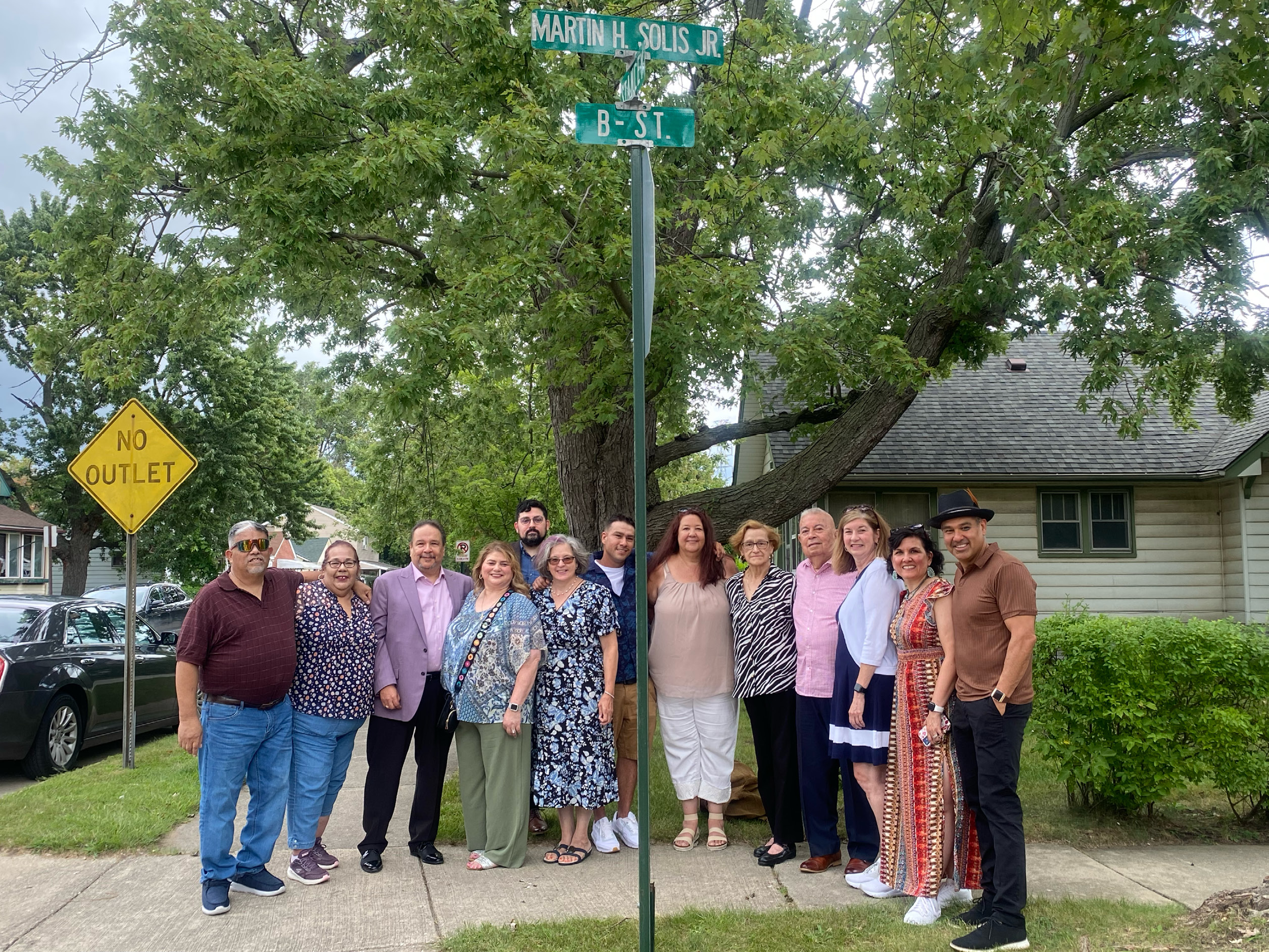 Family and friends of Martin Solis Jr. stand beneath the new street sign.